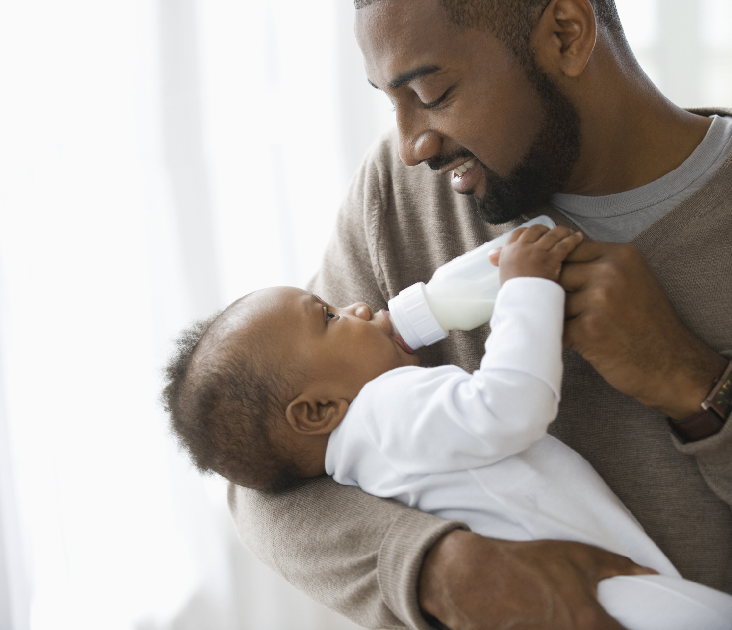 Father looking & bottle feeding baby good technique