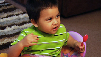 Toddler at table talking and squirming while he eats