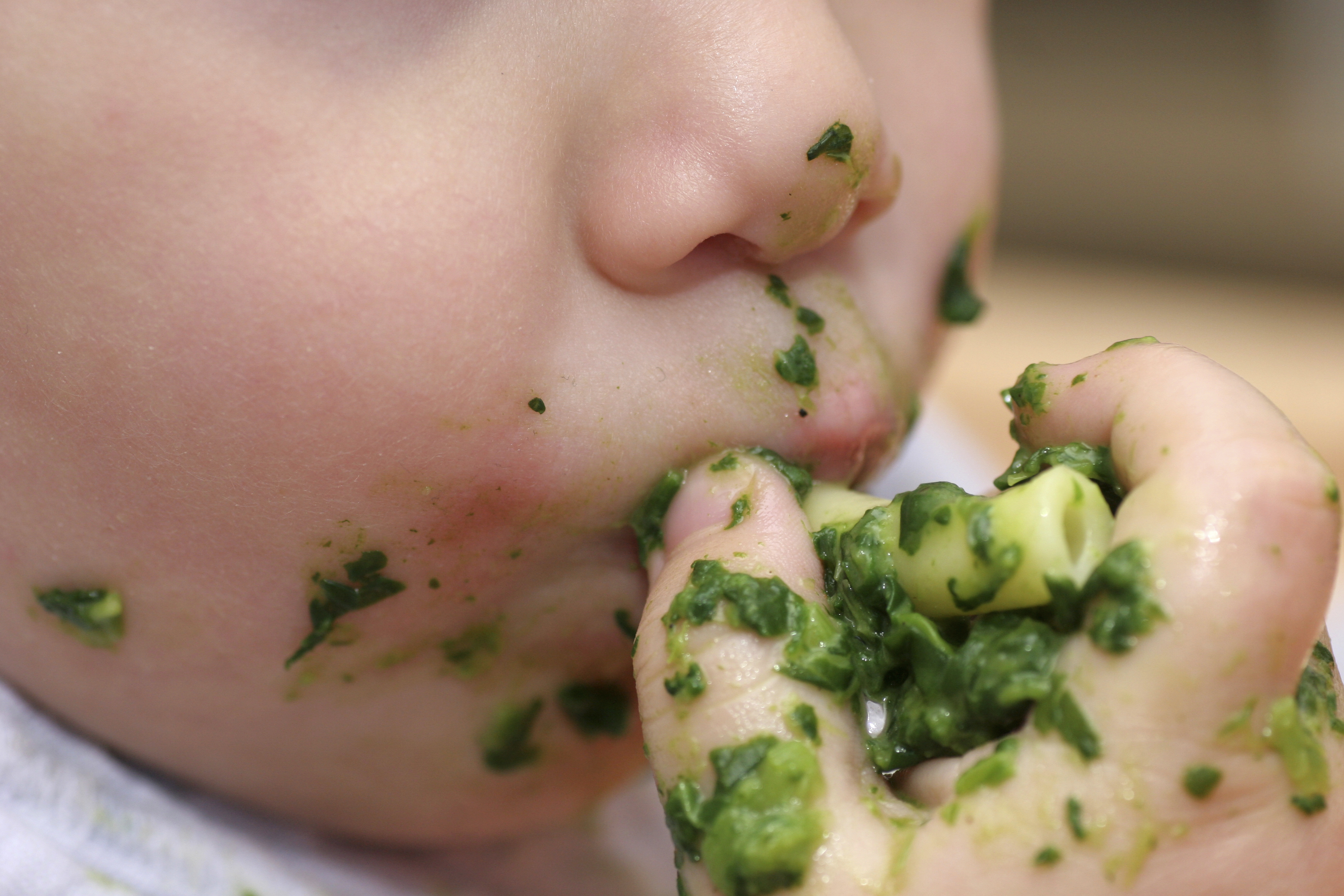 Closeup of messy hands and mouth of older baby eating pasta Closeup of messy hands and mouth of older baby eating pasta