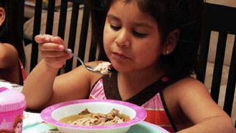 Preschooler sitting up nicely regarding food as she prepares to eat